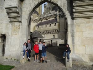 Four children plus a woman stand in a castle archway