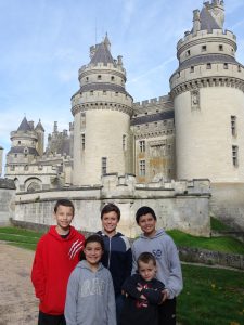 five kids stand in front of a pretty castle