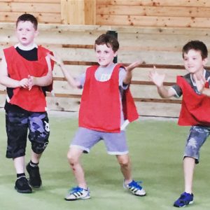 Three boys have fun in a sports hall while playing a game at Eurocamp's kids club